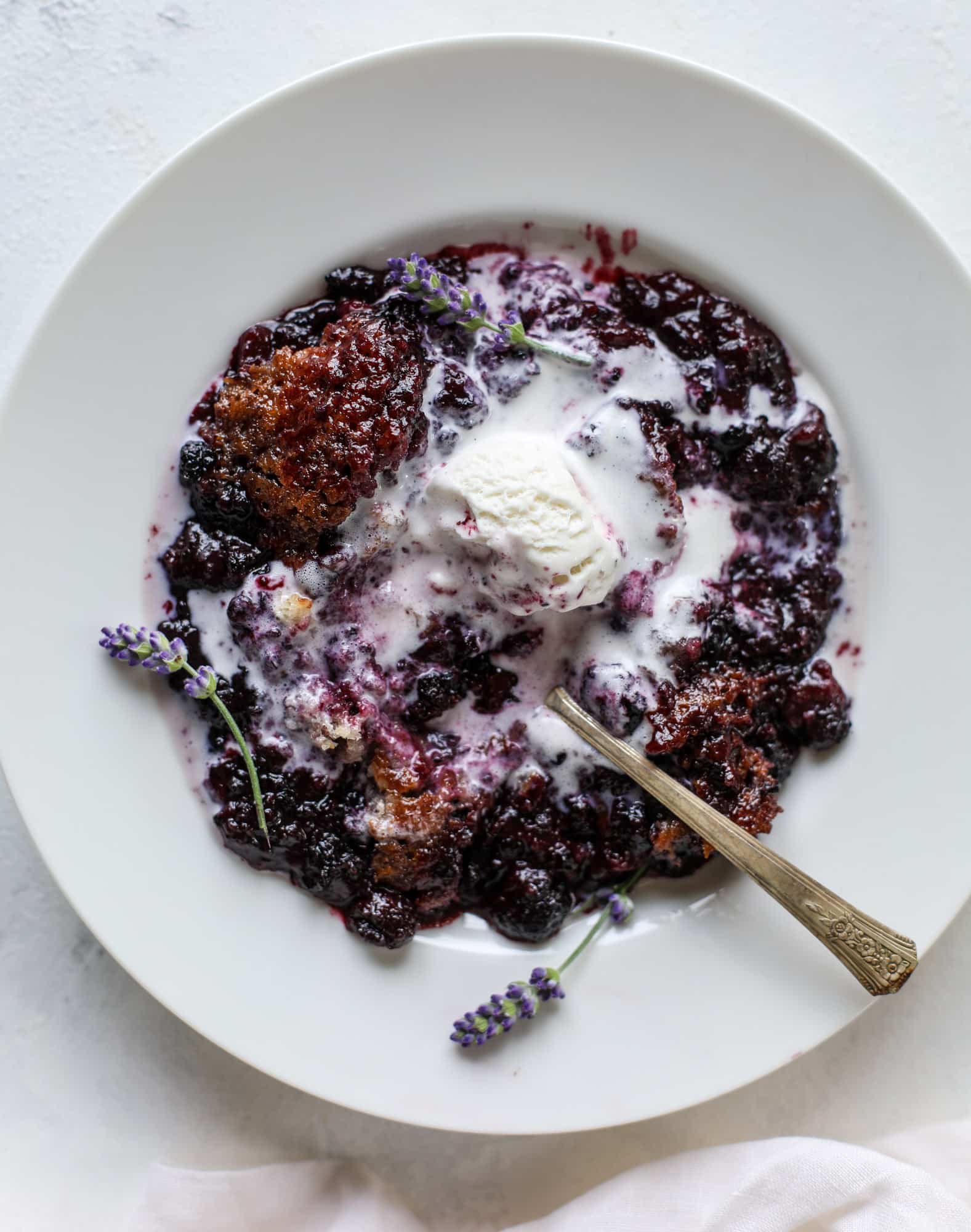This black raspberry cobbler is a summer dream come true! The bursting black raspberries are rich and sweet, then add in a touch of lavender for incredible flavor and you're all set. The cobbler cake topping is perfect for vanilla ice cream. Win! I howsweeteats.com #black #raspberry #cobbler #lavender #summer #desserts #icecream