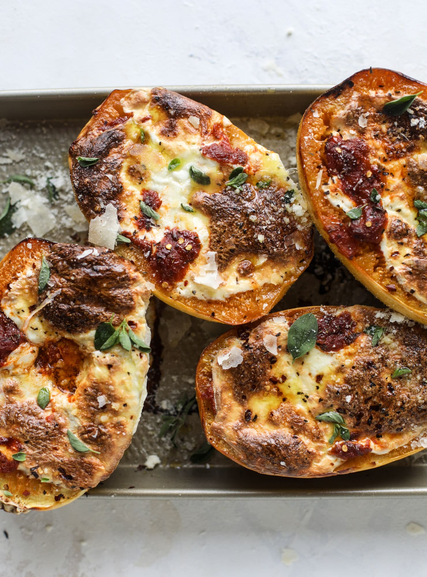 Spaghetti squash parmesan is a delicious weeknight meal! Topped with marinara or bolognese, melty cheese and fresh herbs, it's easy and delicious! I howsweeteats.com #spaghettisquash #parmesan